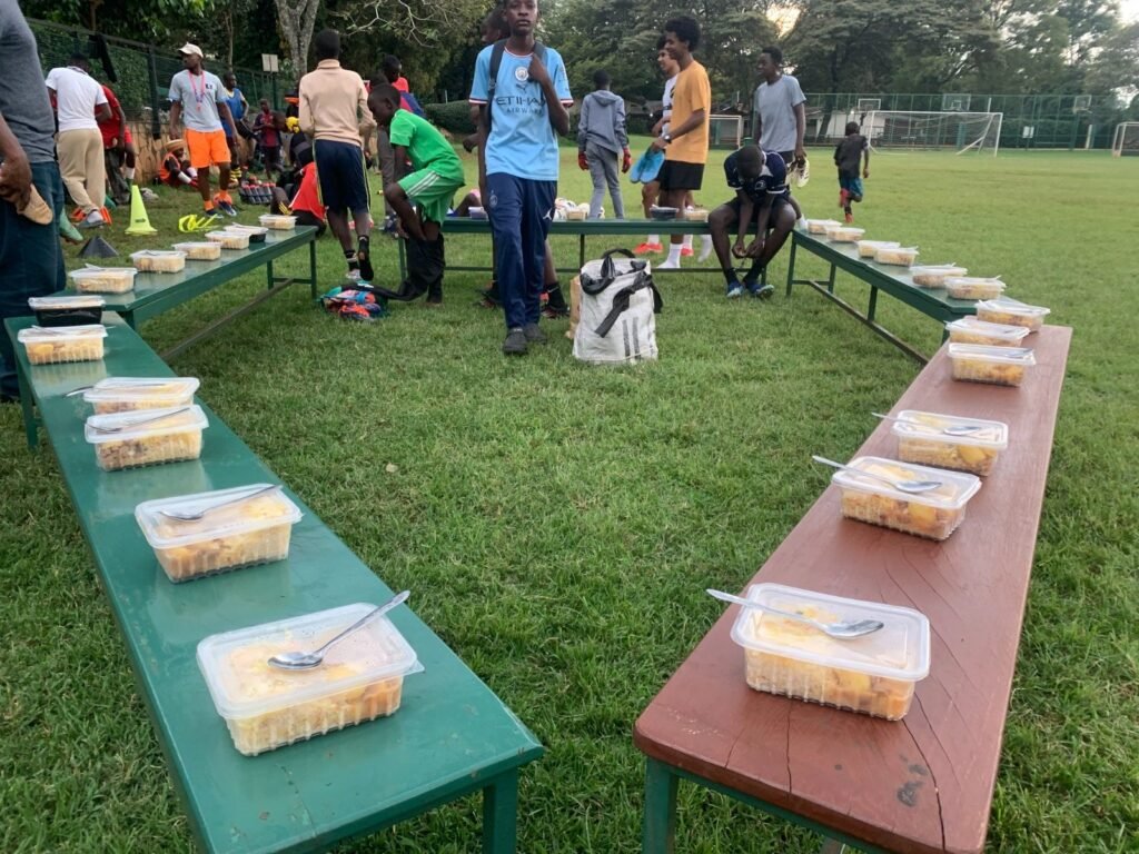 Rows of packed meals laid out on benches beside the pitch after a Kisasa FC training session.